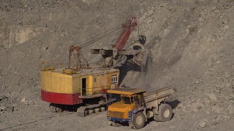 A huge mining excavator pours soil into the body of a large multi-ton yellow Stock Footage 125576291