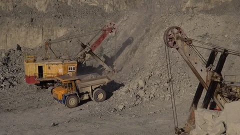A huge mining excavator pours soil into the body of a large multi-ton yellow Stock Footage 125579072
