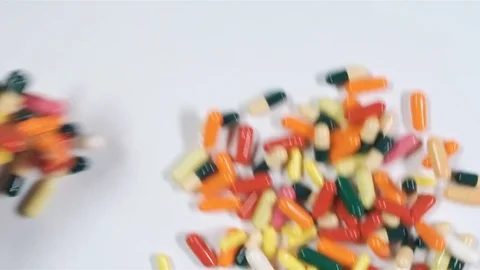 A huge number of pills falling on white background top view in slow motion. Stock Footage 72862068