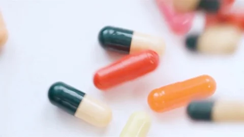 A huge number of pills falling on white background top view in slow motion. Stock Footage 72864635