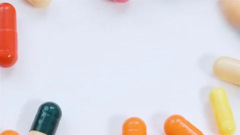 A huge number of pills falling on white background top view in slow motion. Video stock 72896302