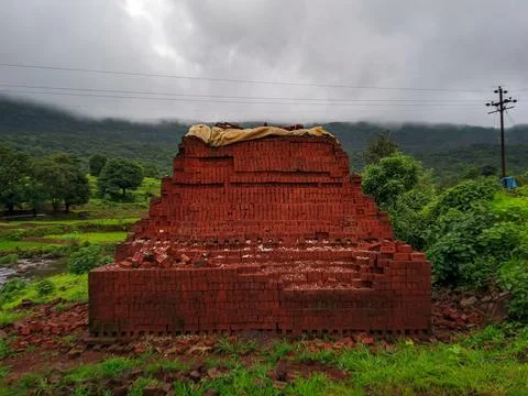 Huge pile of red bricks surrounded by green at rural site Stock Photos