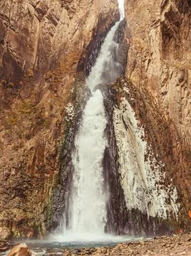 A huge powerful waterfall flows down between the steep cliffs of the Caucasian Stock Photos