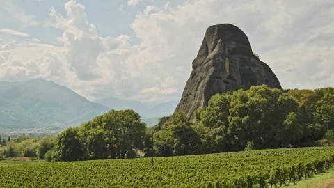 Huge Prominent triangular shape rock rises from Greek vineyard landscape Stock Footage 290781520