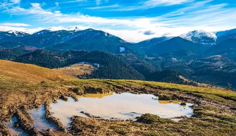 A huge puddle of mud on a path in the Carpathian mountains against the backdr 库存照片