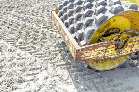 Huge road roller with spikes is compacting soil at construction site Stock Photos