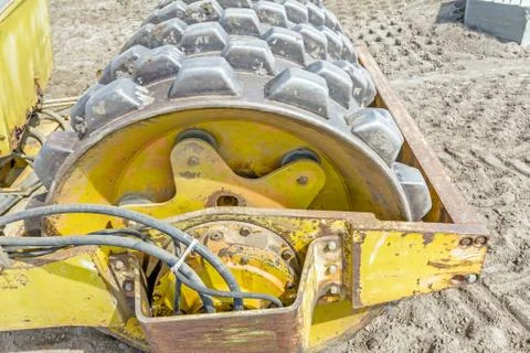 Huge road roller with spikes is compacting soil at construction site Stock Photos