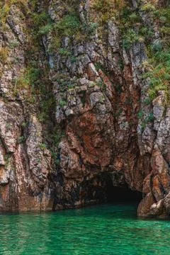 Huge rocks with greenery hang over a small beach Vrbnik Croatia 27.06.2024 Stock Photos