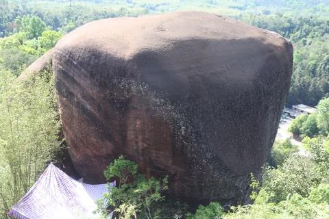 Huge rounded boulder rising above a forested hillside Stock-Fotos