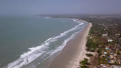 Huge sandy beach with waves crashing, vegetation and buildings along the coast Video stock 208936991