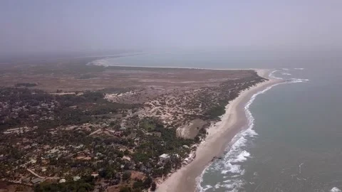 Huge sandy beach with waves crashing, vegetation and buildings along the coast Stock Footage 208936996