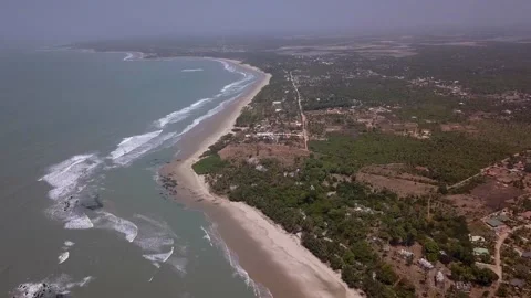 Huge sandy beach with waves crashing, vegetation and buildings along the coast Video stock 208937001