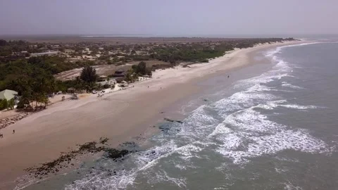 Huge sandy beach with waves crashing, vegetation and buildings along the coast Stock Footage 208937007