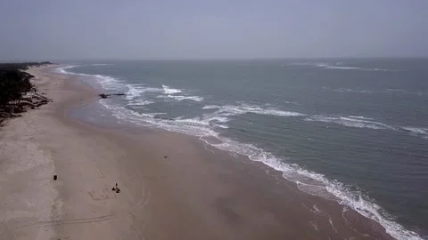 Huge sandy beach with waves crashing and a few people walking Stock Footage 208937018