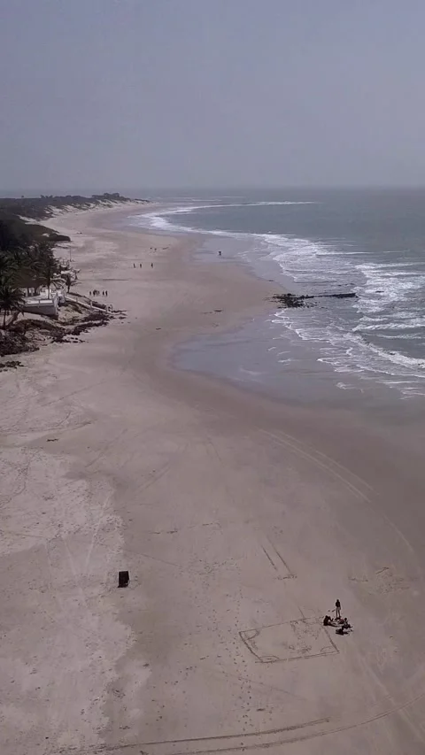 Huge sandy beach with waves crashing and a few people walking Stock Footage 230671332