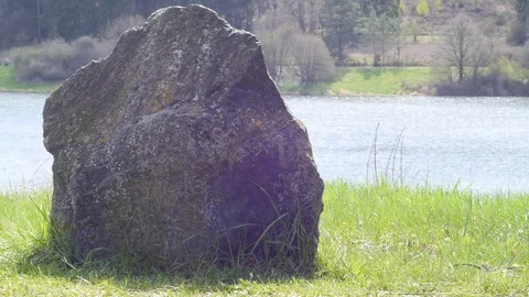 Huge stone on the grass against the river background Stock Footage 74314169