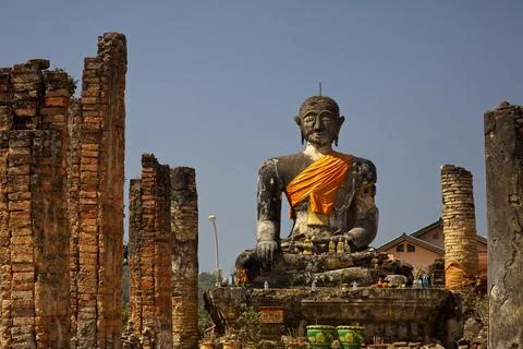 Huge stone statute of buddha looking forward wrapped in orange clock monastry Stock Photos