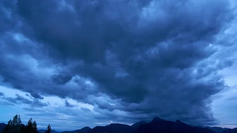 A huge storm cloud forms over the mountains at dusk. Twilight transition to Stock Footage 167974742