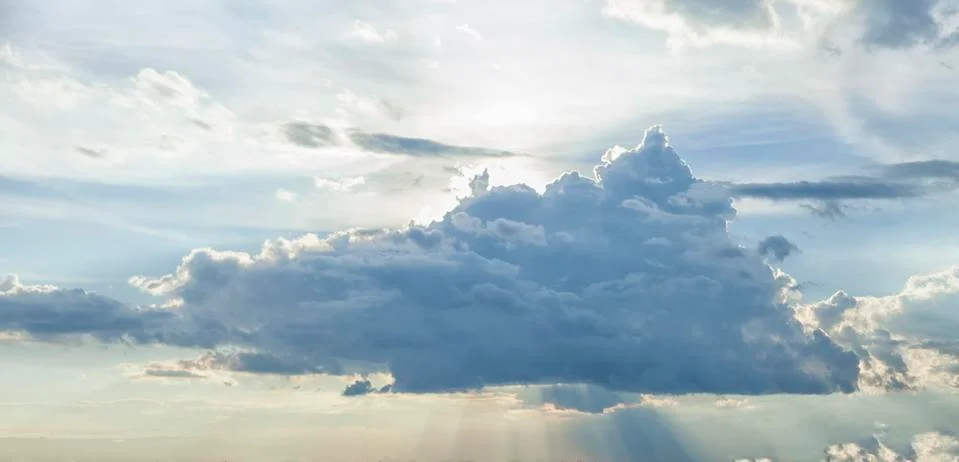 A huge storm cloud with sun rays emanating from it in the sky Stock Photos