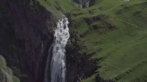 Huge Swiss waterfall surrounded by snowy mountains Stock Footage 123711022