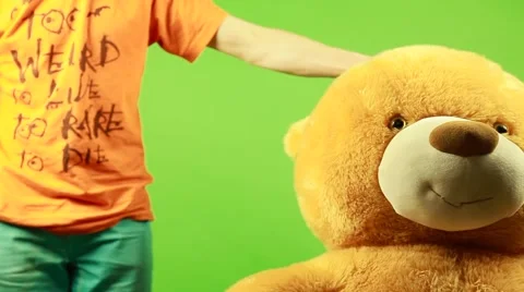 Huge teddy bear moves on a green background and play with pumpkin Stock Footage 63210124