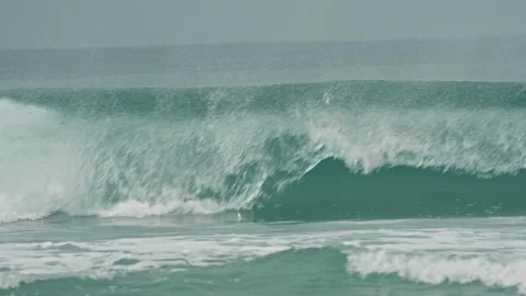 Huge turquoise wave creating a barrel and then crashing with immense force Video stock 344572366