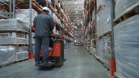 A huge warehouse with goods. The worker in uniform and helmet moves on the Stock-Footage 111767783
