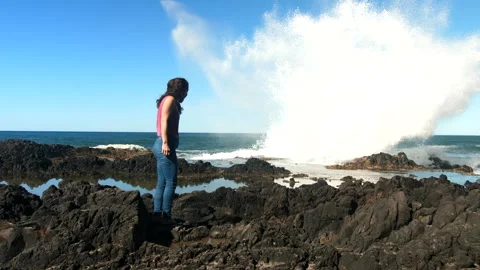 Huge wave crashes and splashes high while women watches in amazement. Stock Footage 247332910