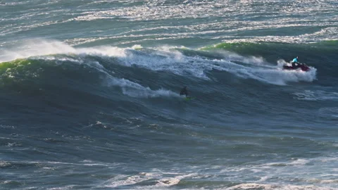 Huge waves carrying a surfer who tries to conquer them extreme sport. Nazare Stock Footage 305106525