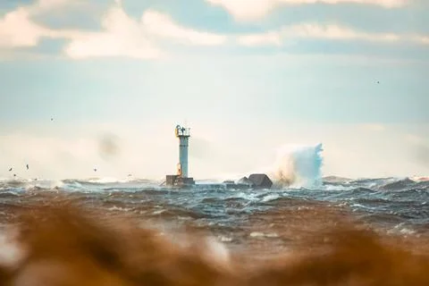 Huge waves crashing down the lighthouse during the storm. Stormy weather by.. Stock Photos
