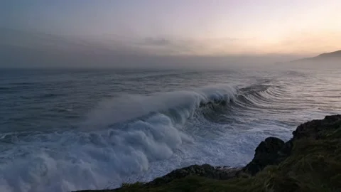Huge waves with massive force crashing against the rocks at sunrise Stock Footage 142307069