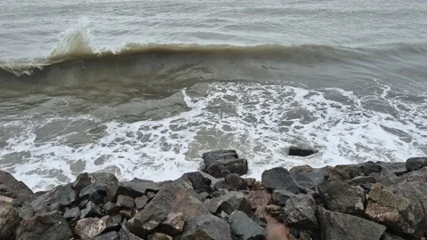 Huge waves reaching the shoreline rocks and splashing in the air Video stock 302584829