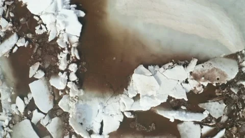 A huge white block of ice immersed in muddy water. Fragments of melting ice on Stock Footage 152901155