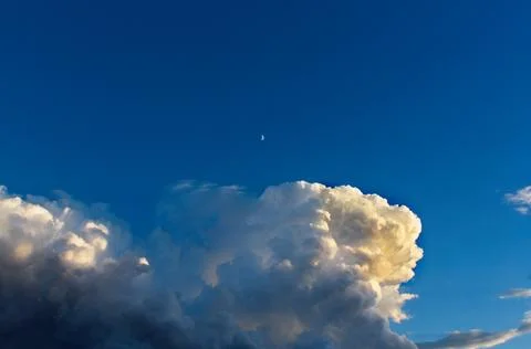Huge white storm cloud forming with the moon in the sky. Stock Photos