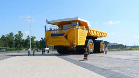Huge yellow mining dump truck parked on paved area with people walking by. Stock Footage 337529850
