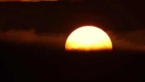 A huge yellow round sun sets behind black clouds Stock Footage 255041781
