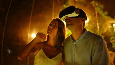 A hugging and talking couple inside transparent bubble tent at glamping at night Stock Footage 250360586