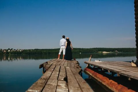 Hugging man and woman in love on wooden pier Stock Photos