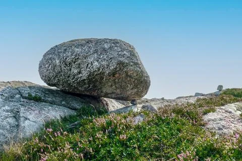 Hugh rock resting on a tiny little stone Stock Photos