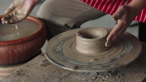 Human adding water from bowl to clay on throwing wheel Stock Footage 303736626