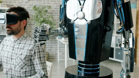 Human and robotic arm doing same movements, guy in vr glasses testing machine Stock Footage 119817894