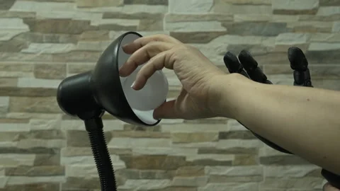 Human and Robotic or Prosthesis Hand Changing Light Bulb in Desk Lamp Stock Footage 340382864