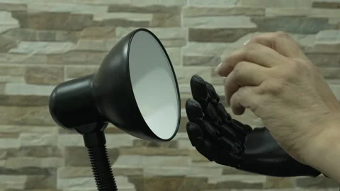 Human and Robotic or Prosthesis Hand Changing Light Bulb in Desk Lamp Stock Footage 340550735