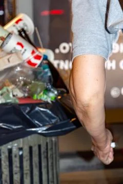 Human arm standing next to a full trash with plastic. Russia - 02 August 2026 Stock Photos