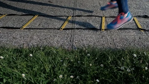 A human being in sneakers jumps through rods with ropes on the asphalt Stock Footage 75920706