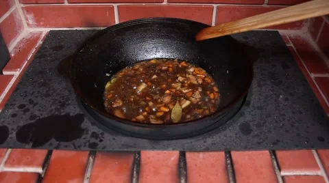 Human controls cooking and stir it with a wooden paddle, front view Stockbeeldmateriaal 56315826