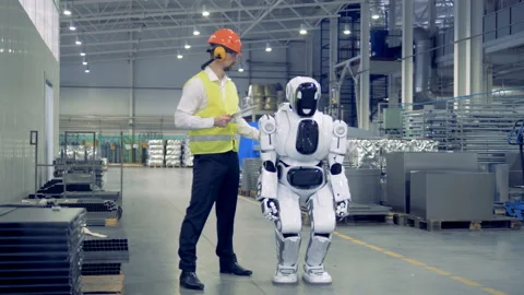 Human-like cyborg is getting switched on and set up by a male factory worker Stock Footage 89229942
