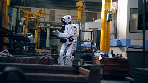 Human-like cyborg is using a tablet in factory premises Stock Footage 106847478