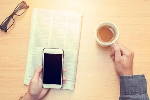 Human drinking coffee He's using Mobile phone (vintage tone) Stock Photos