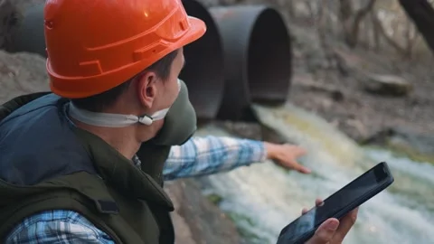 A human ecologist, an engineer in a helmet and a respirator with a tablet Vidéo 132388599